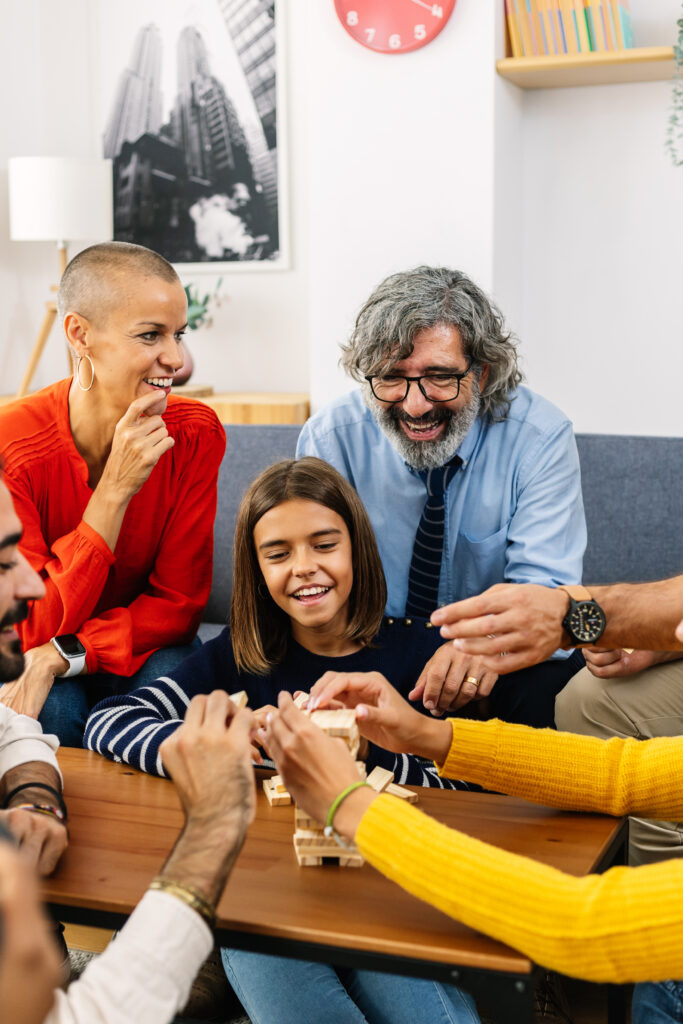 Happy group of multigenerational family having fun playing block game at home